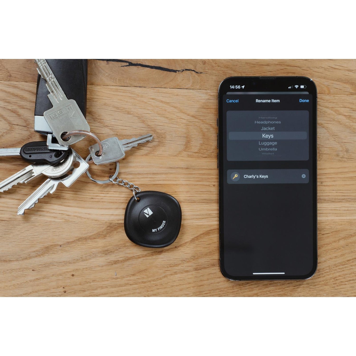 Schwarzer, runder Verbatim Bluetooth Tracker aus Kunststoff am Schlüsselbund neben einem iPhone mit "Keys"-Auswahl.
