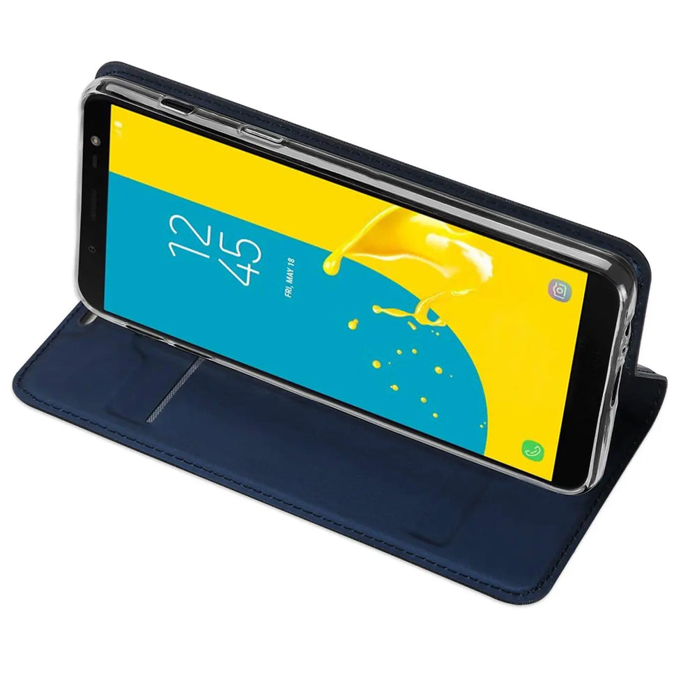 Samsung Galaxy J6 2018 in dunkelblauer Kunstleder-Flip-Hülle, aufgestellt als Ständer, schräg von oben.