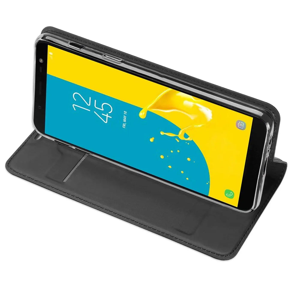 Samsung Galaxy J6 2018 in schwarzer, klappbarer Kunstlederhülle, schräg von oben als Ständer aufgestellt.