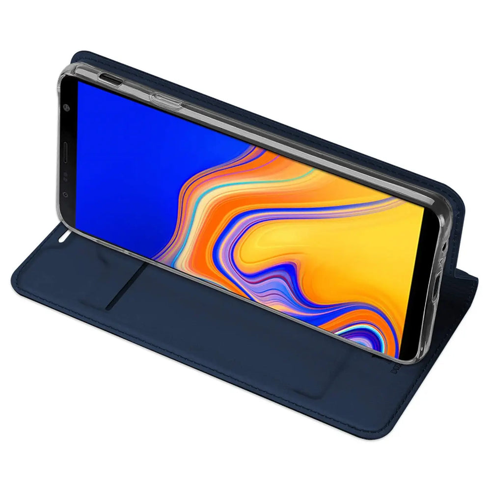 Samsung Galaxy J6 Plus in dunkelblauer Metallic Flip Hülle, als Ständer aufgestellt, schräg von oben.