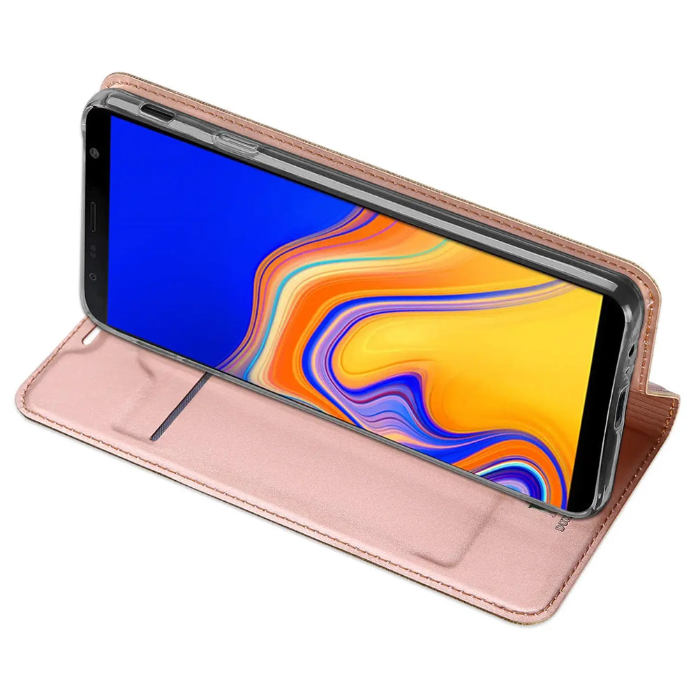 Samsung Galaxy J6 Plus in roségoldener Metallic Flip Hülle aus Kunstleder, als Ständer aufgestellt, schräg von oben.