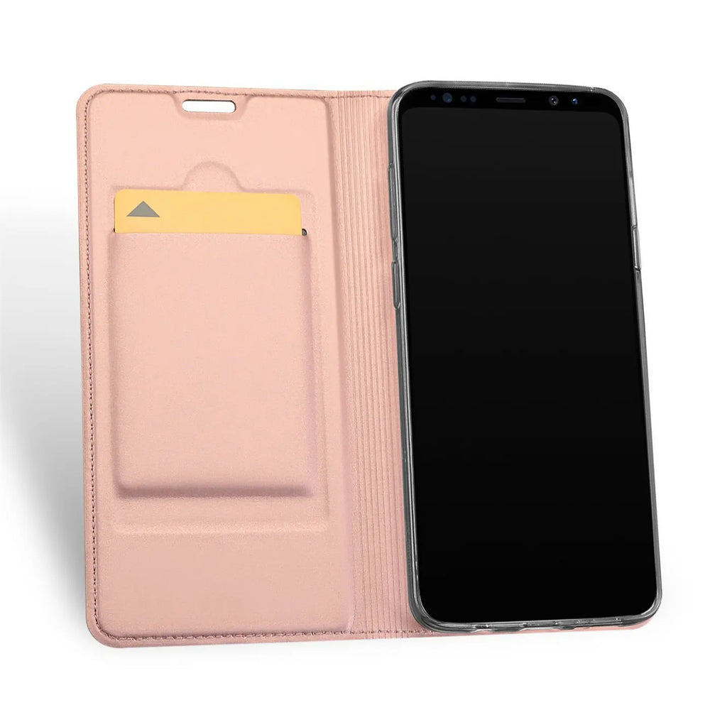 Offene rosafarbene Kunstleder-Flip-Hülle mit Samsung Galaxy S10e und gelber Karte im Fach, schräg von oben.
