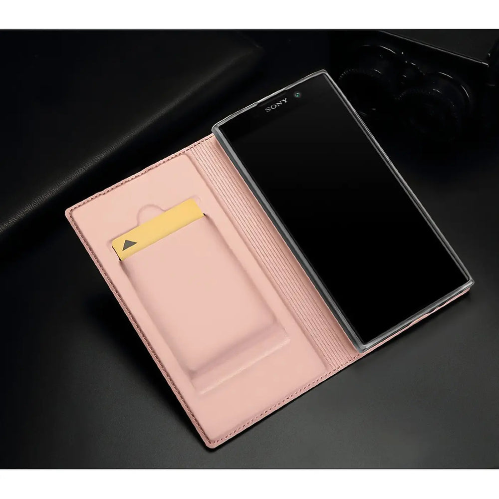 Offene rosa Kunstleder Flip Hülle mit Sony Xperia XA2 Smartphone und goldener Karte im Fach, schräg von oben.