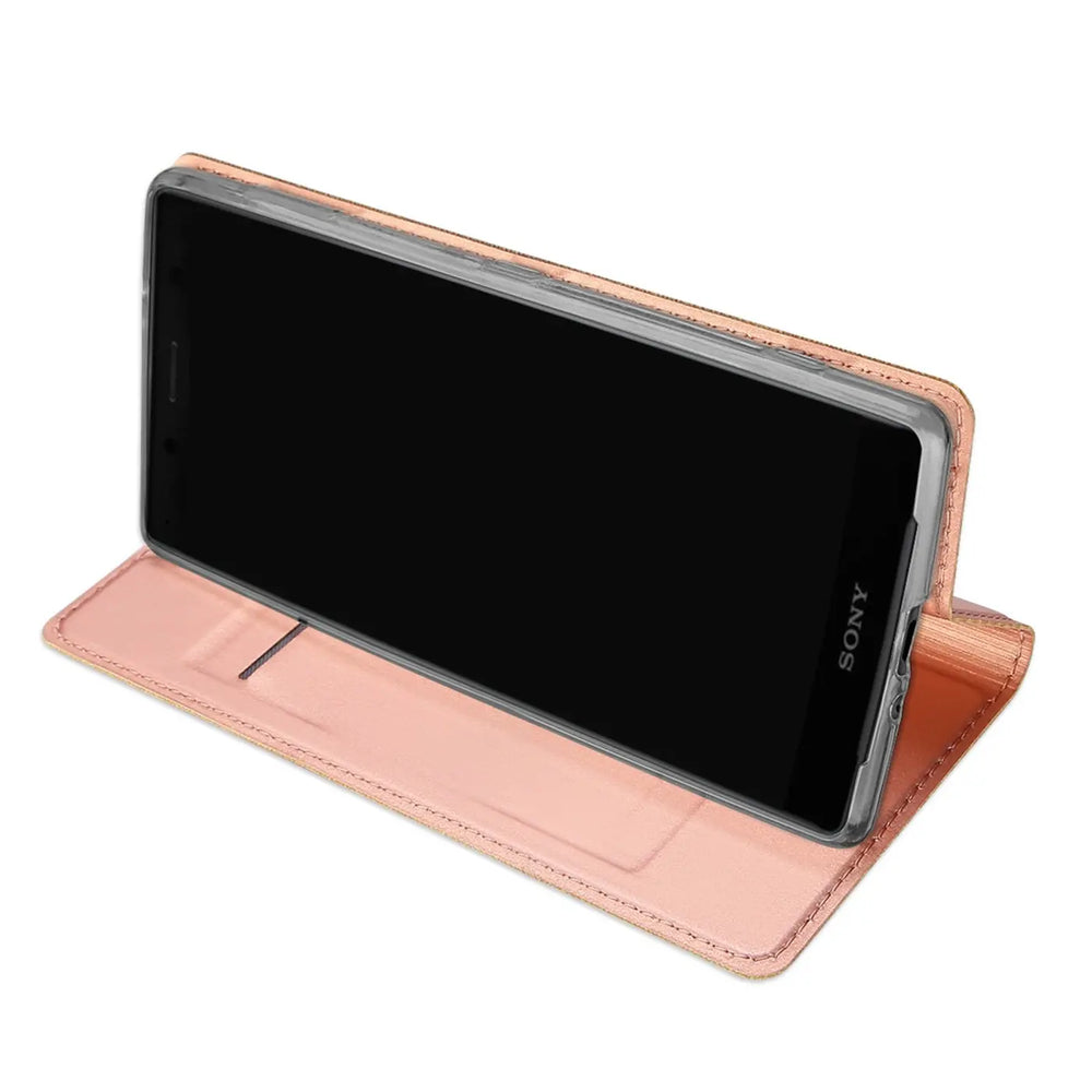 Sony Xperia XZ2 Compact in roségoldener Kunstleder Flip Hülle, als Ständer aufgestellt, schräg von vorne.