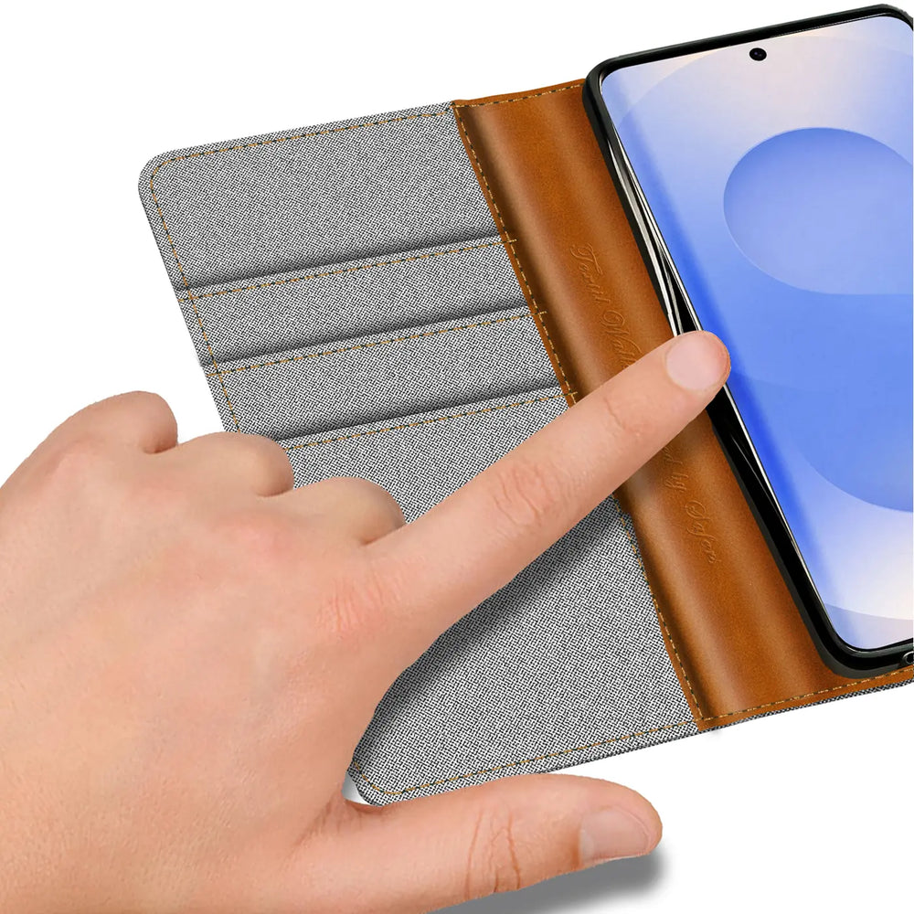 Graue Textil-Klapphülle mit braunen Lederdetails, Kartenfach, Finger auf Samsung S25 Edge.