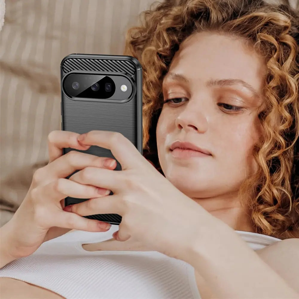 Junge Frau hält ein Google Pixel 7 in einer schwarzen Carbon-Hülle mit gebürsteter Textur, Kamera von hinten sichtbar.