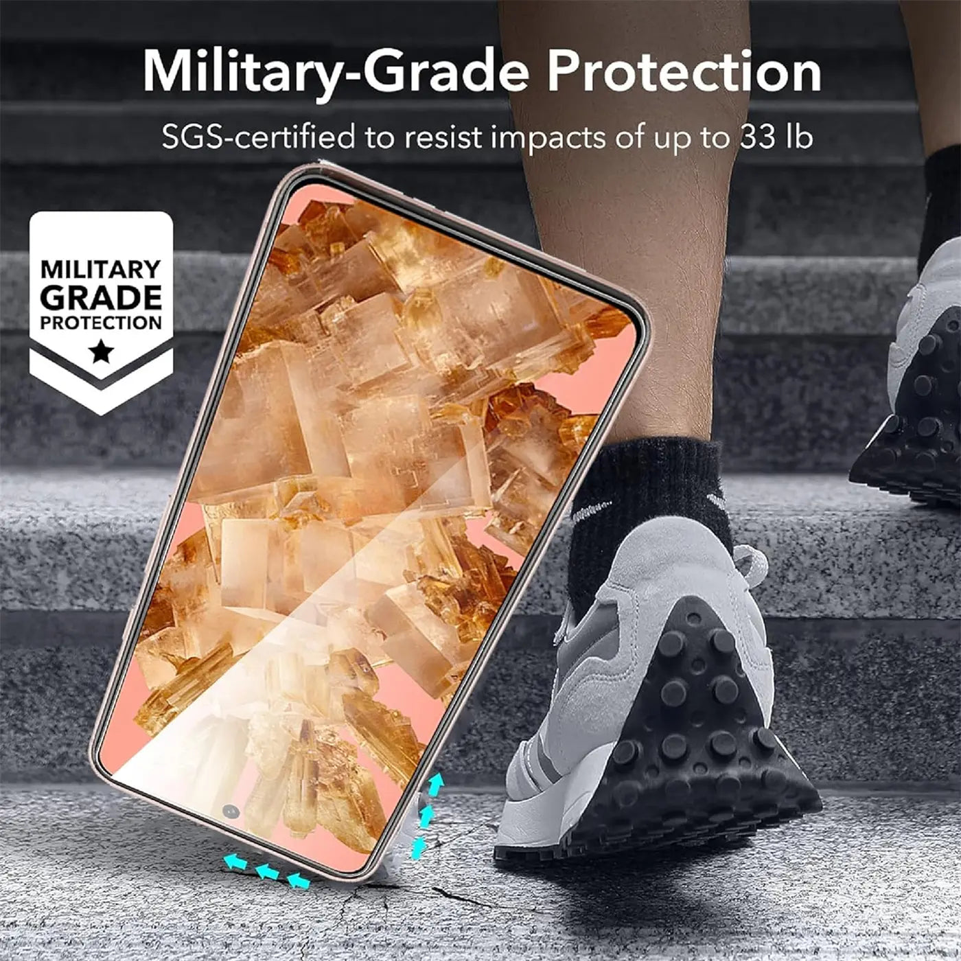 Google Pixel 8a mit transparentem Schutzglas, schräg auf grauem Boden, im Hintergrund Bein und Schuh.