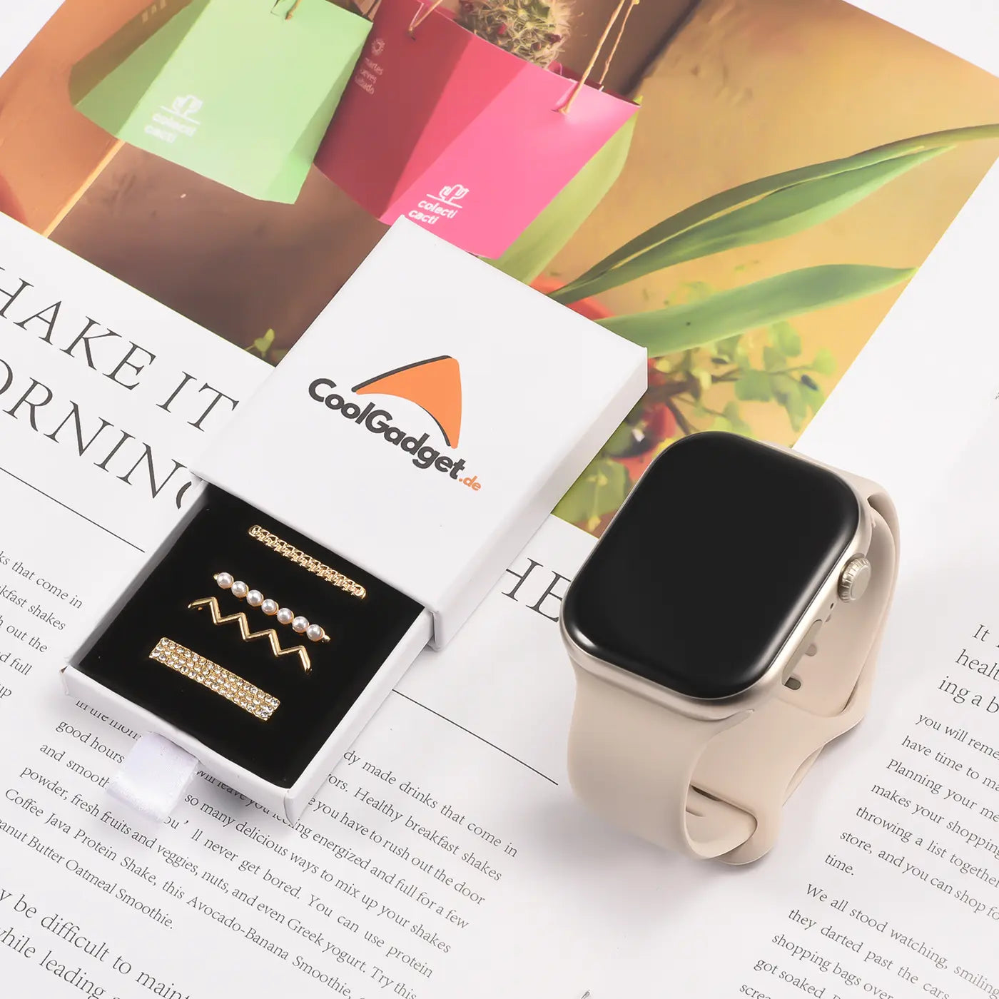 Goldene Smartwatch-Armbandschmuck-Sets mit Perlen und Zirkonia in Schachtel, neben heller Smartwatch.