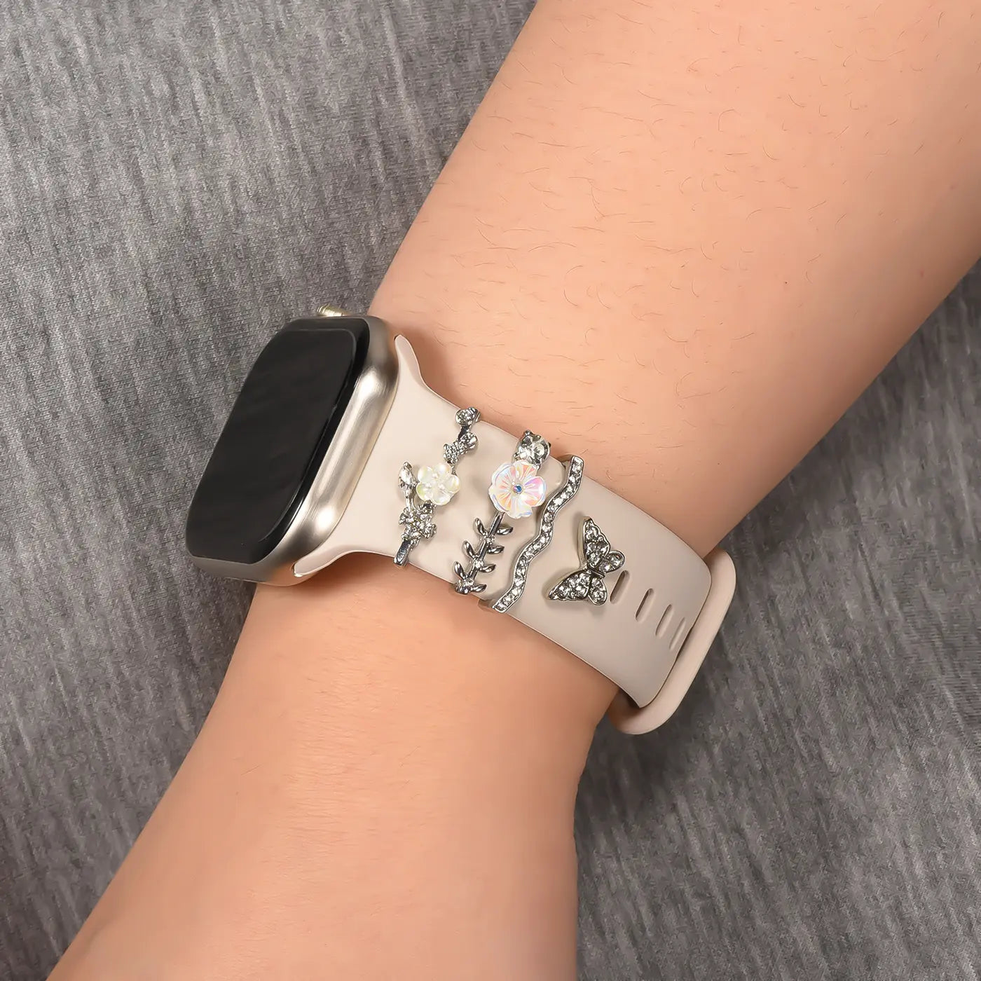 Beige Smartwatch-Armband mit Blumen- und Schmetterlings-Charms aus Metall und Strass.