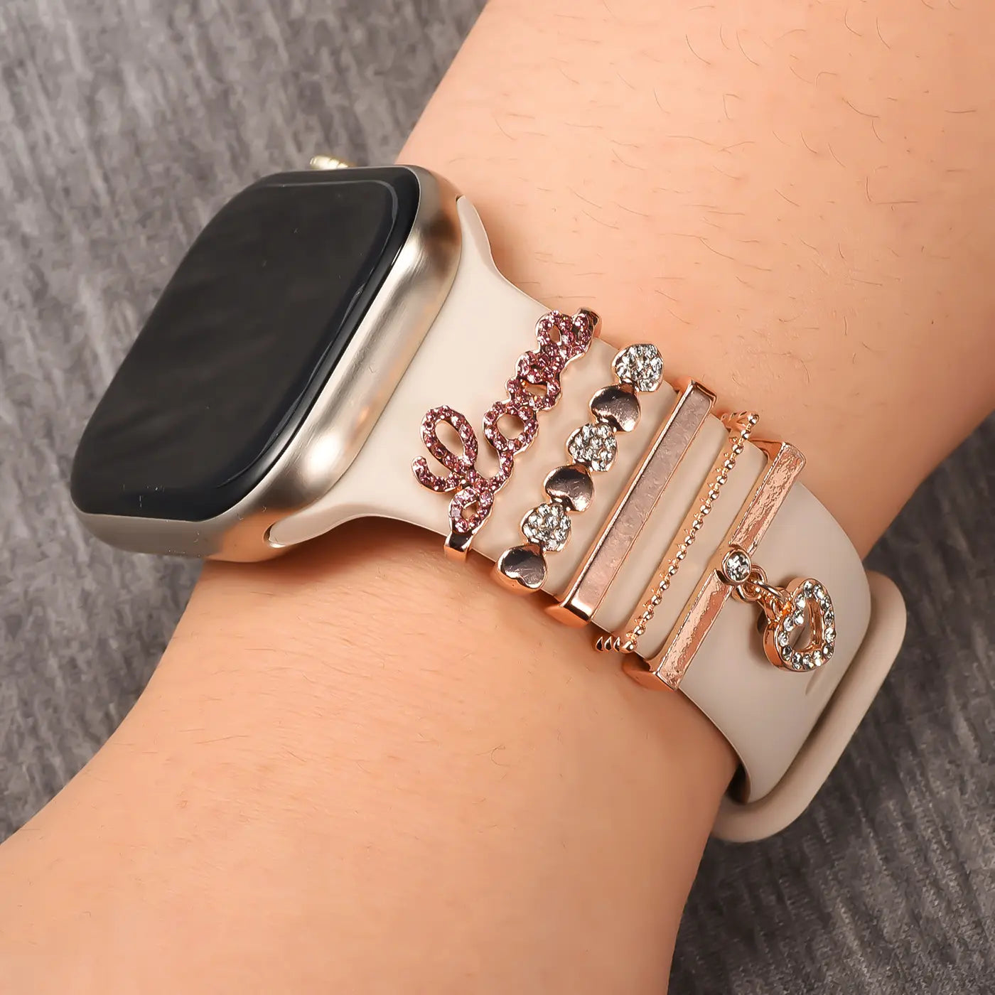 Smartwatch-Armband beige mit roséfarbenen Charms: "Love", Herzen, Ringe. Nahaufnahme.