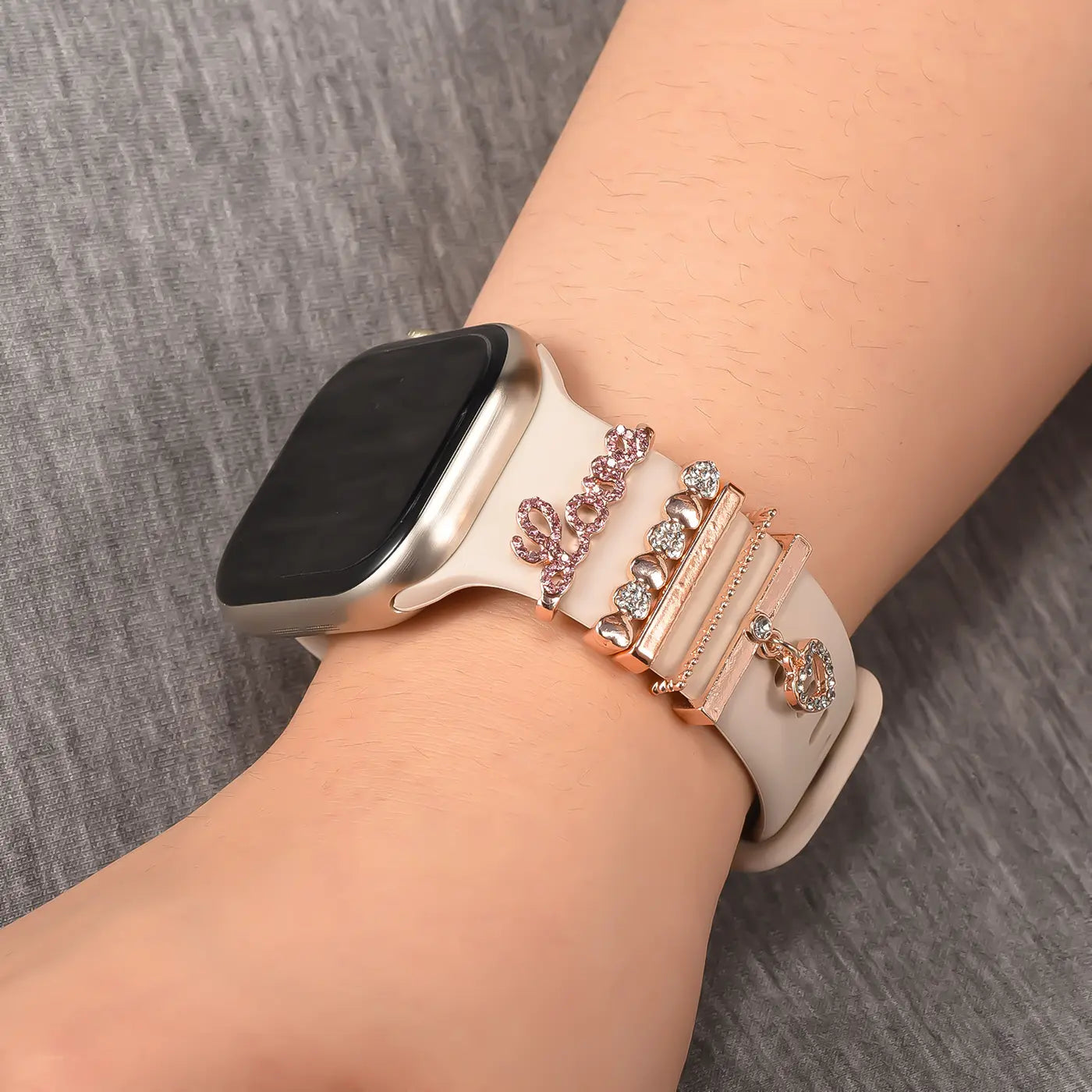 Smartwatch-Armband in Beige mit roségoldenen Charms und Kristallen, Nahaufnahme von der Seite