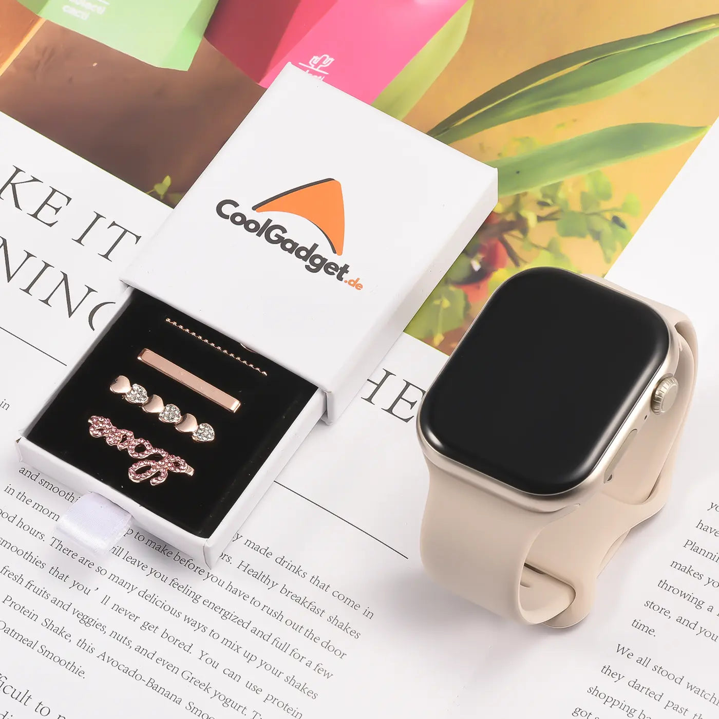Smartwatch-Armbandschmuck aus Metall in Roségold mit Herzen und Perlen, neben einer Smartwatch.