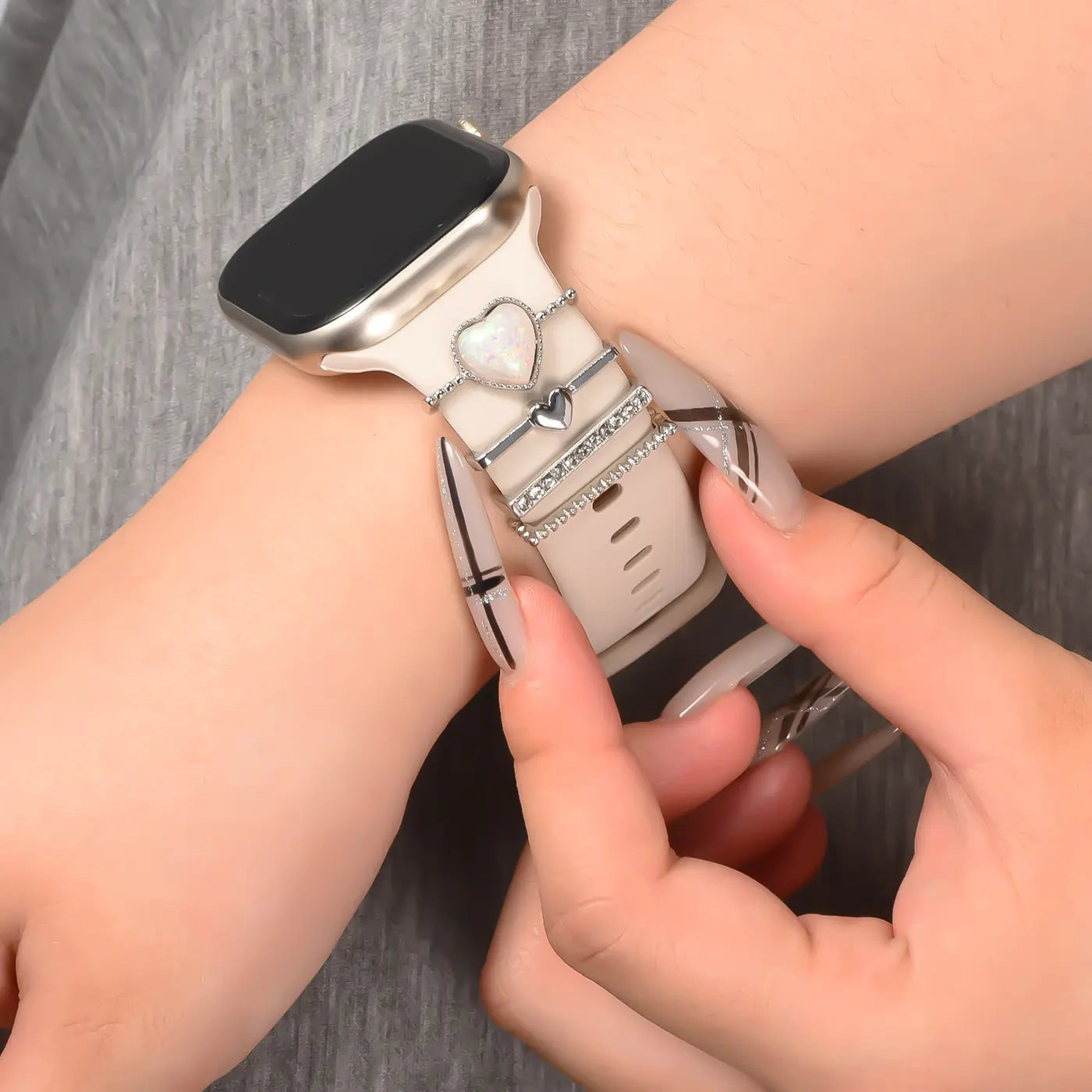 Smartwatch-Armband, beige, mit silbernen Charms (Herz, Ringe), Nahaufnahme, von vorne