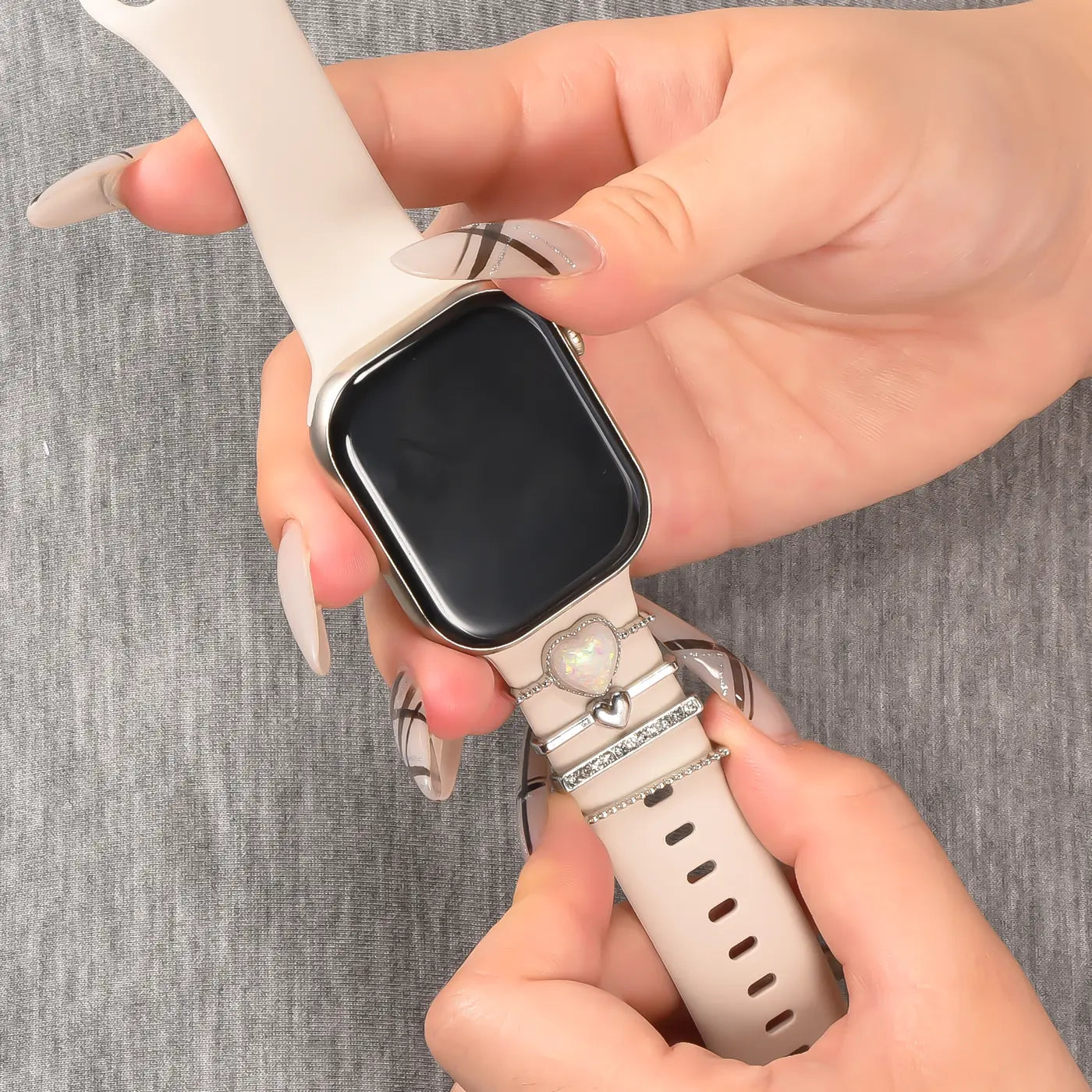 Hände mit Smartwatch und Armbandschmuck (Herz-Anhänger, Metall)
