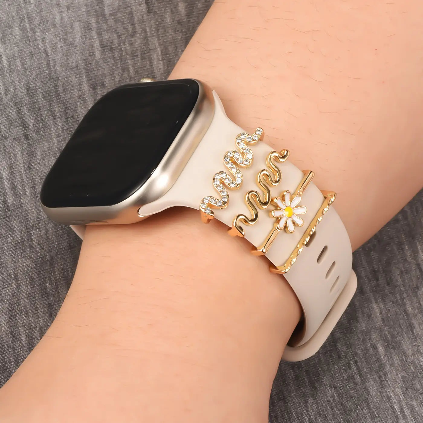 Smartwatch-Armband beige mit goldenen Charms: Schlangen, Blume, Strass. Nahaufnahme.