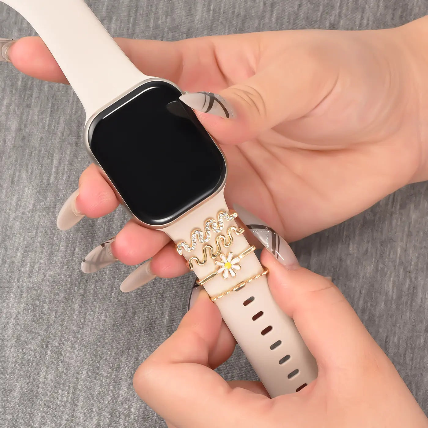 Beige Smartwatch-Armband mit goldenen Charms, Nahaufnahme, von oben