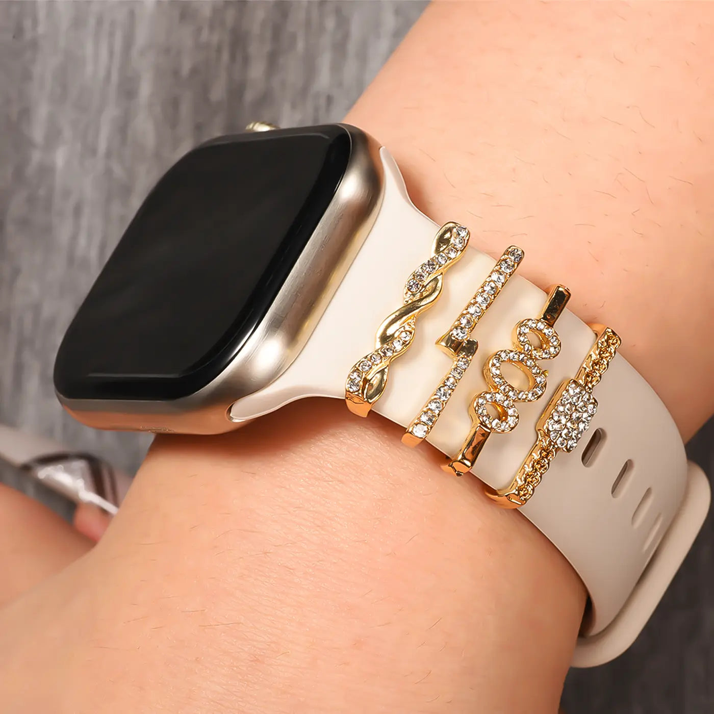 Goldene Smartwatch-Charms mit Strass auf hellem Band, Nahaufnahme von vorne
