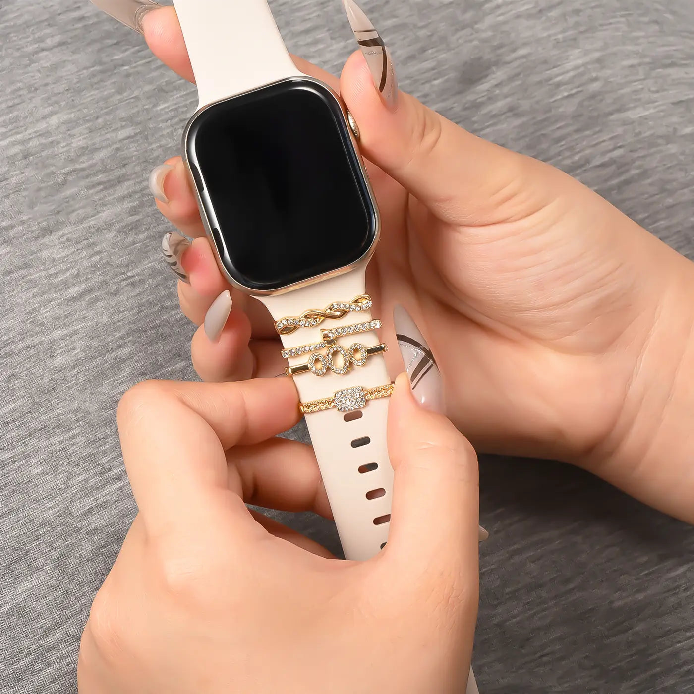 Goldene Smartwatch-Armband-Charms mit Steinen auf hellem Band, Nahaufnahme