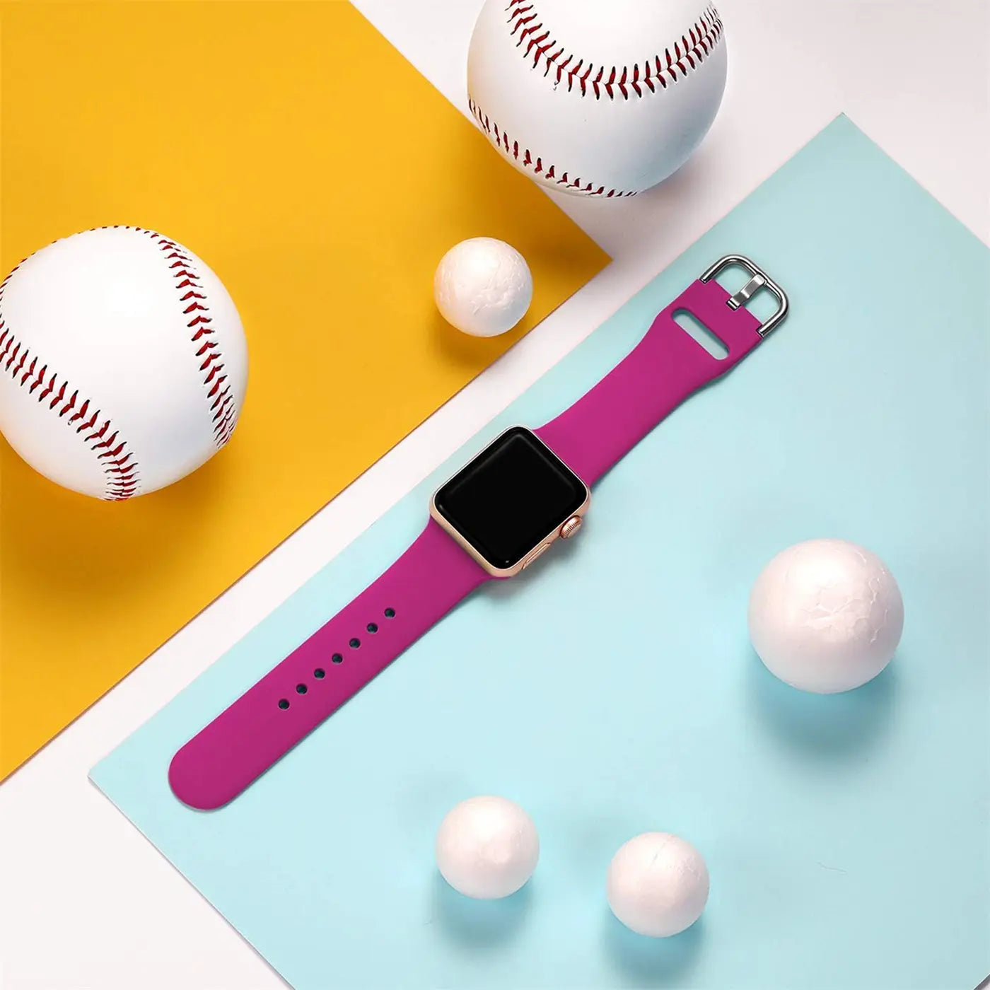 Magenta TPU-Fitnessarmband für Apple Watch, mit goldener Uhr, von oben auf gelb-blauem Hintergrund mit Bällen.