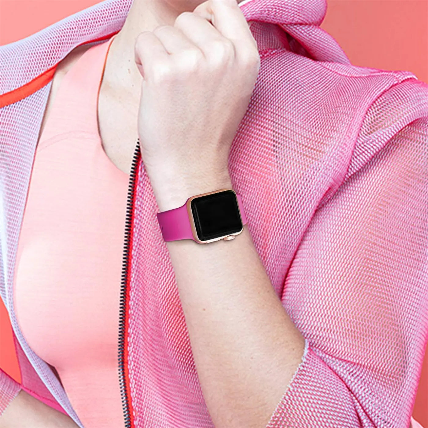 Frau trägt pinkes TPU-Armband an goldener Apple Watch am linken Handgelenk, von vorne, leicht schräg.