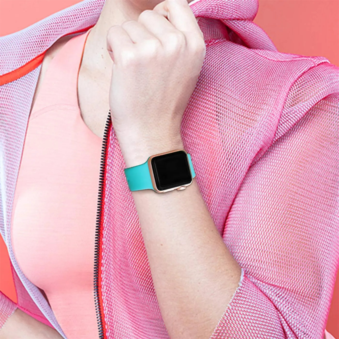 Frau mit goldener Apple Watch und türkisem TPU-Armband am linken Handgelenk, von vorne leicht schräg.