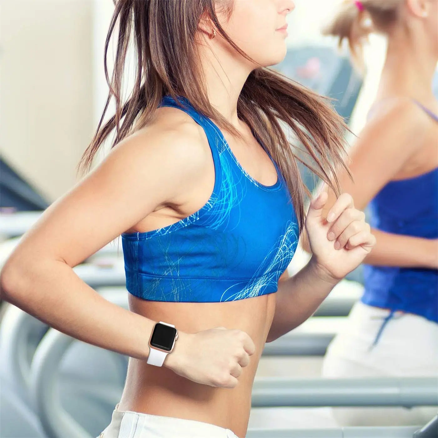 Frau läuft auf Laufband, trägt eine Apple Watch mit weißem TPU-Armband am linken Handgelenk, Seitenansicht.