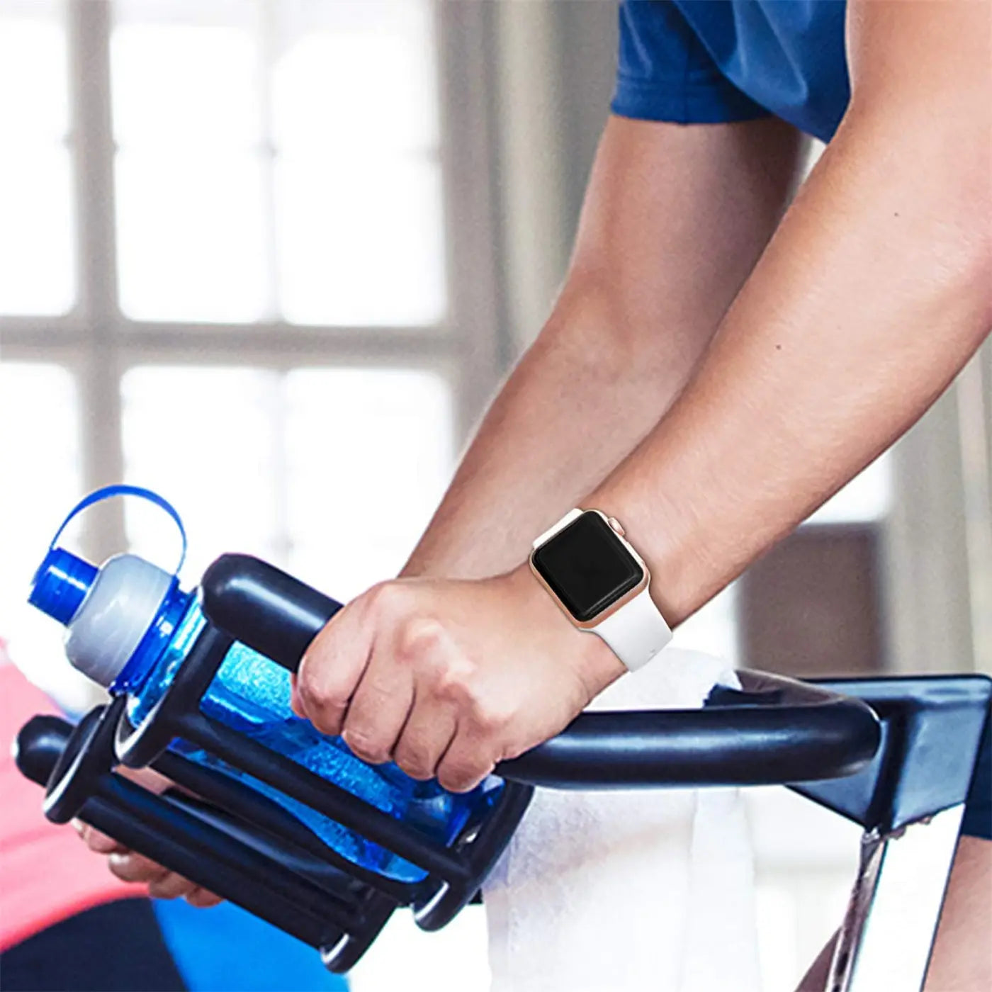 Person auf Ergometer, von oben. Am linken Handgelenk eine Apple Watch mit weißem TPU-Armband und goldener Hülle.