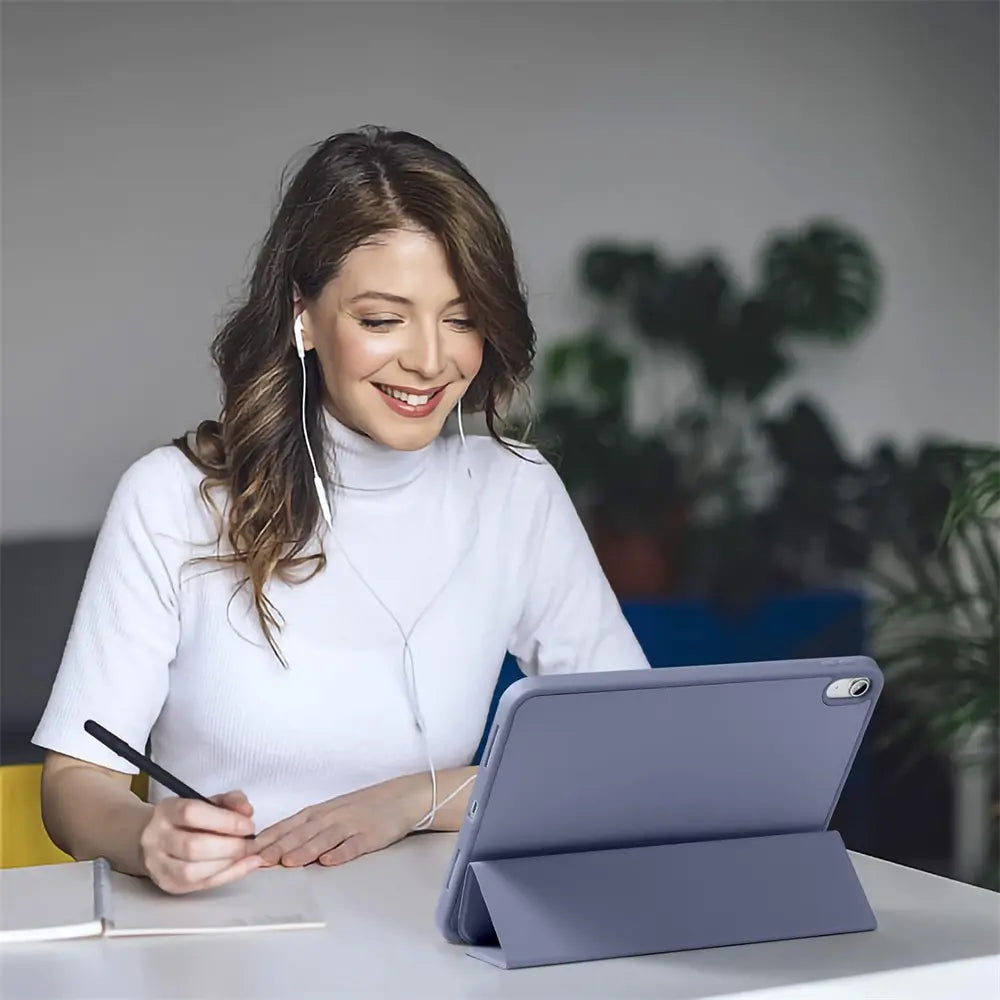 Junge Frau mit Kopfhörern und schwarzem Stift, vor einem aufgestellten 13" iPad Pro (M4) in lila Smart Cover.