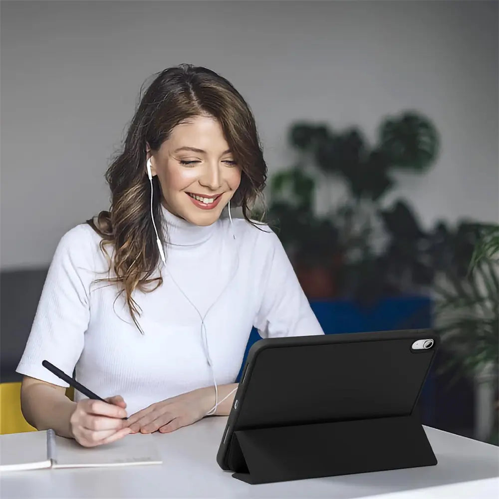 Frau mit Kopfhörern, die lächelnd auf ein schwarzes 13" iPad Pro (M4) mit Smart Cover im Querformat blickt.